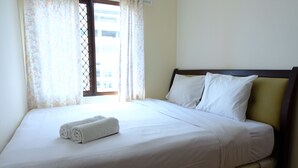 A neatly made bed with white linens and two pillows, a window with floral curtains, and a view of buildings outside. - Scenic 2Br At Grand Setiabudi Apartment (Bandung)
