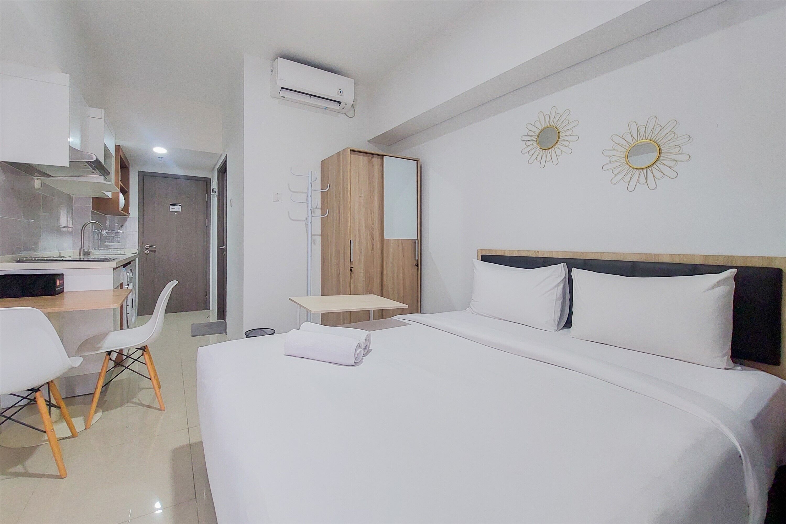 Ein Hotelzimmer mit Bett, Schreibtisch und Stuhl. Im Raum befindet sich ein Kleiderschrank und ein Spiegel an der Wand.