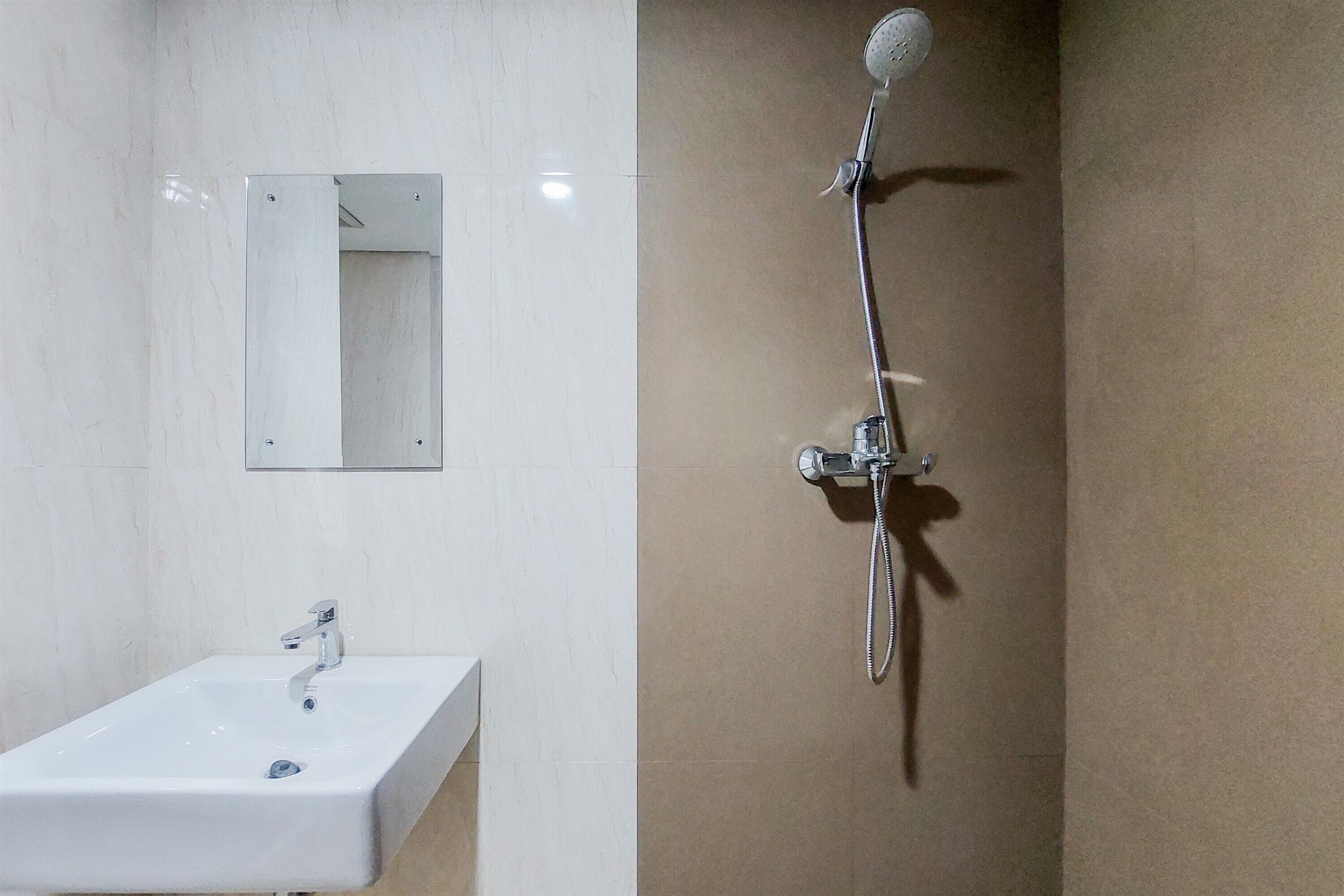 Ein Badezimmer mit weißem Waschbecken, einem Spiegel und einer Dusche inklusive Duschbrause.