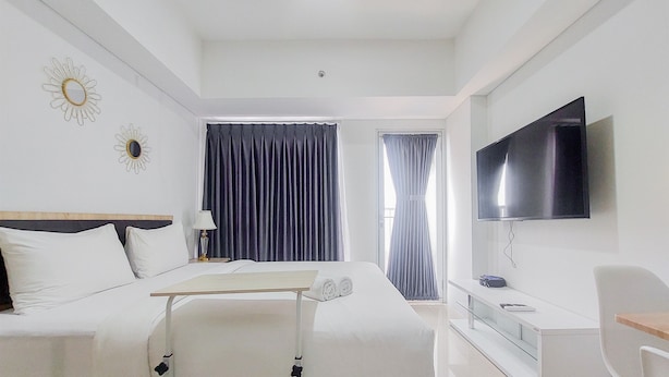 Ein Hotelzimmer mit Bett, Nachttisch, Lampe, Fernseher und Schreibtisch mit Stuhl.