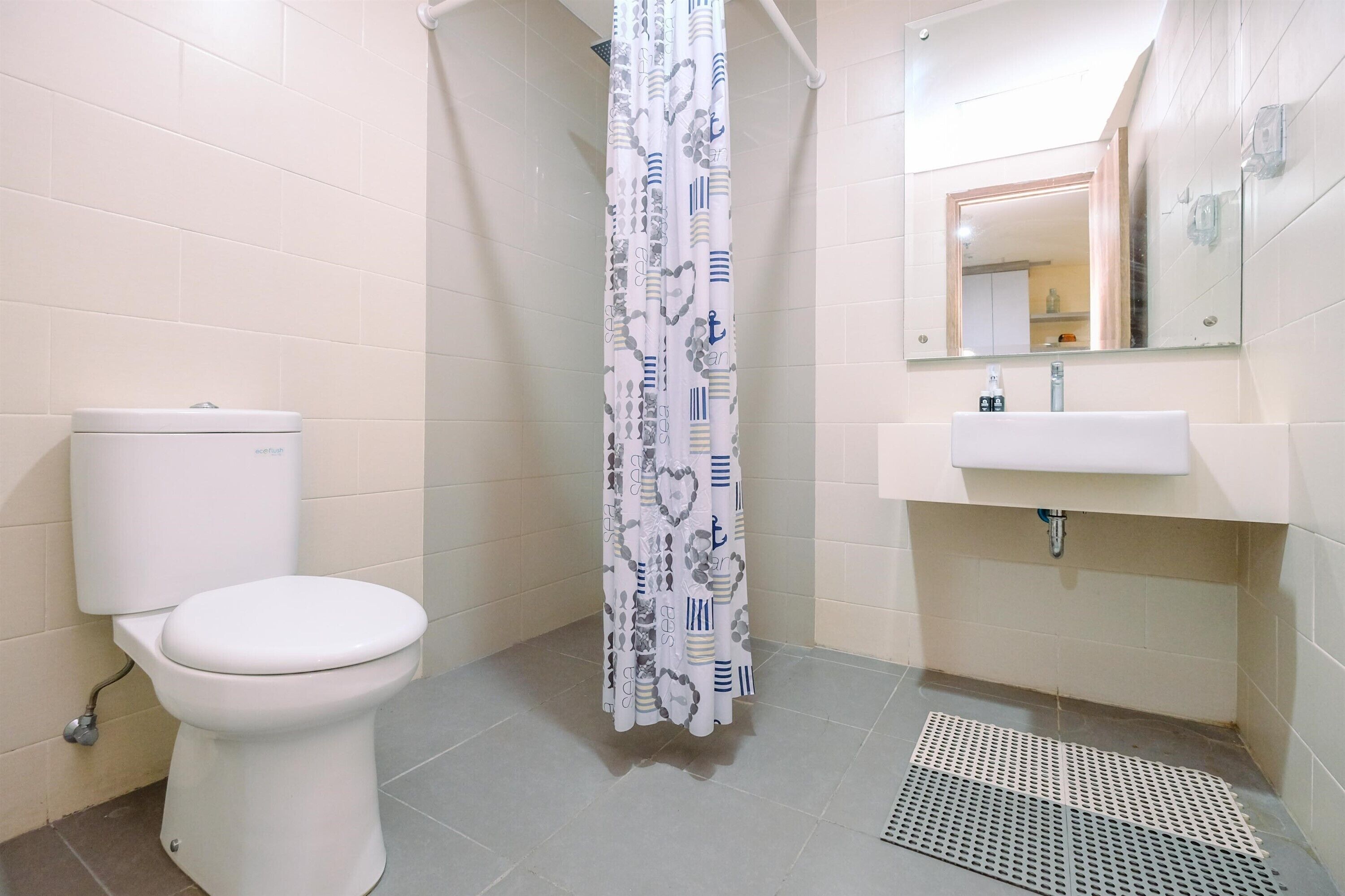 Une salle de bain avec des toilettes, un rideau de douche, un lavabo et un miroir.