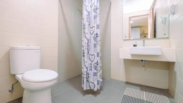 Une salle de bain avec des toilettes, un rideau de douche, un lavabo et un miroir.