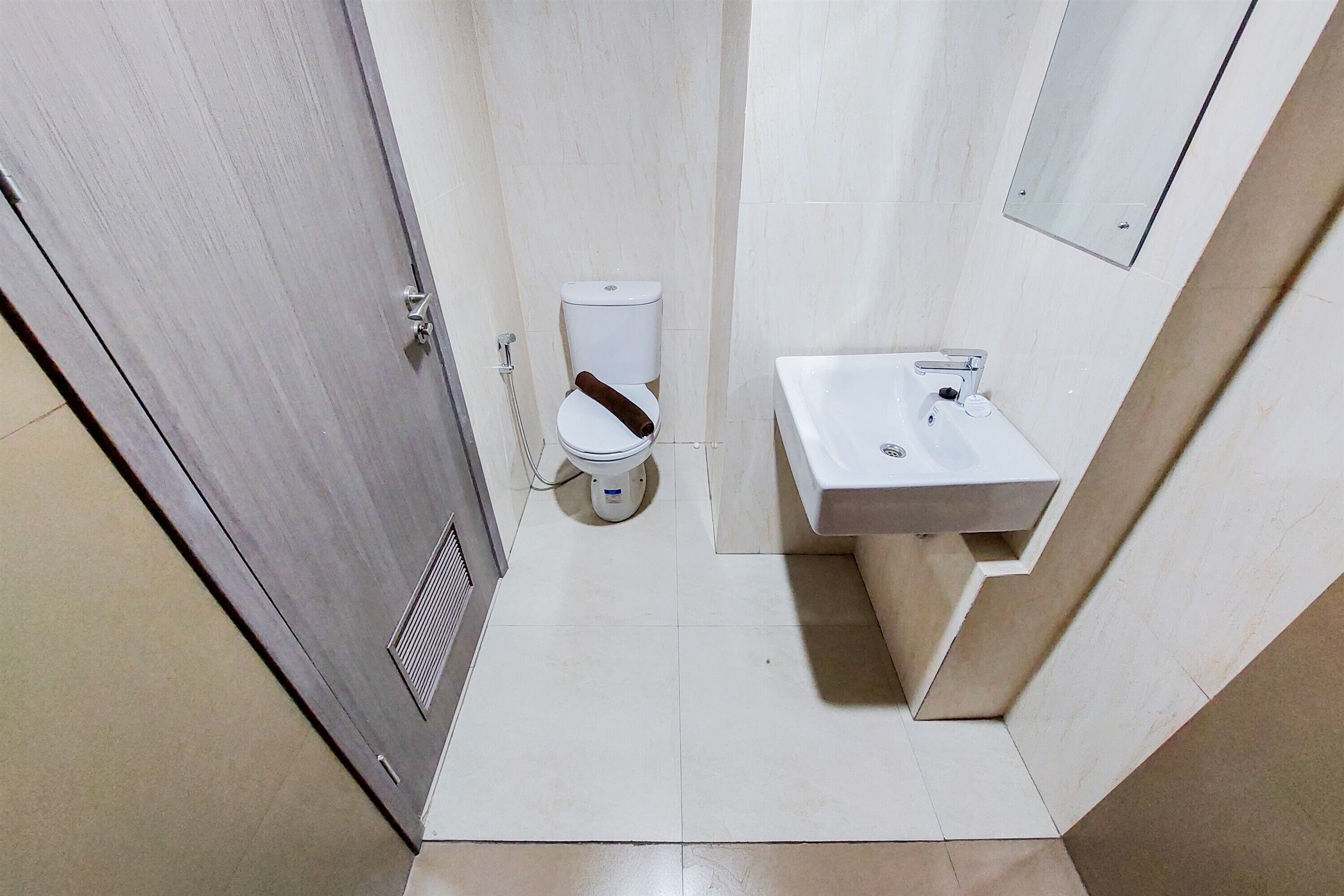 A small, clean bathroom with a toilet, sink, and a mirror.