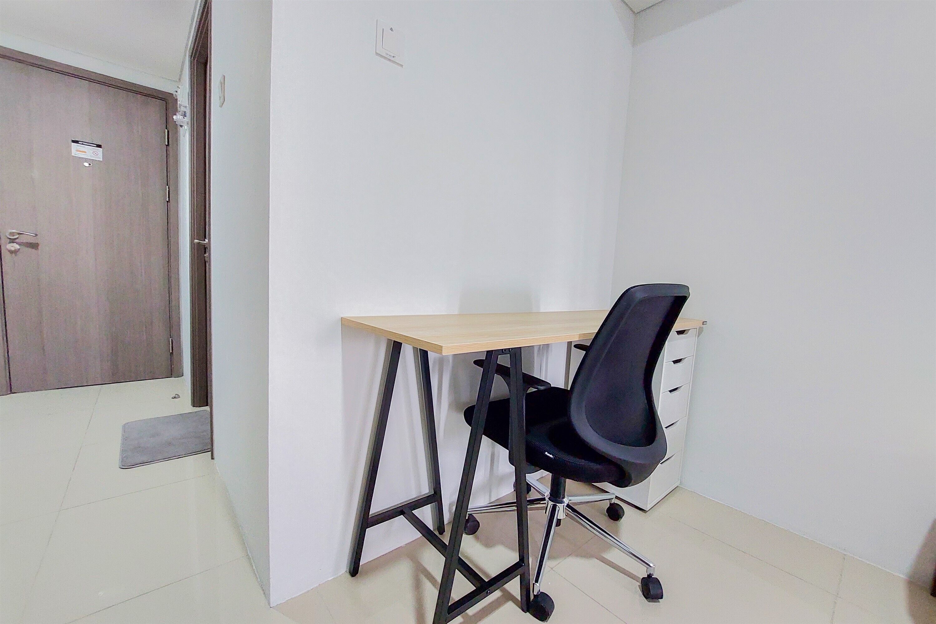 A small office space with a desk, black office chair, and a wooden door.