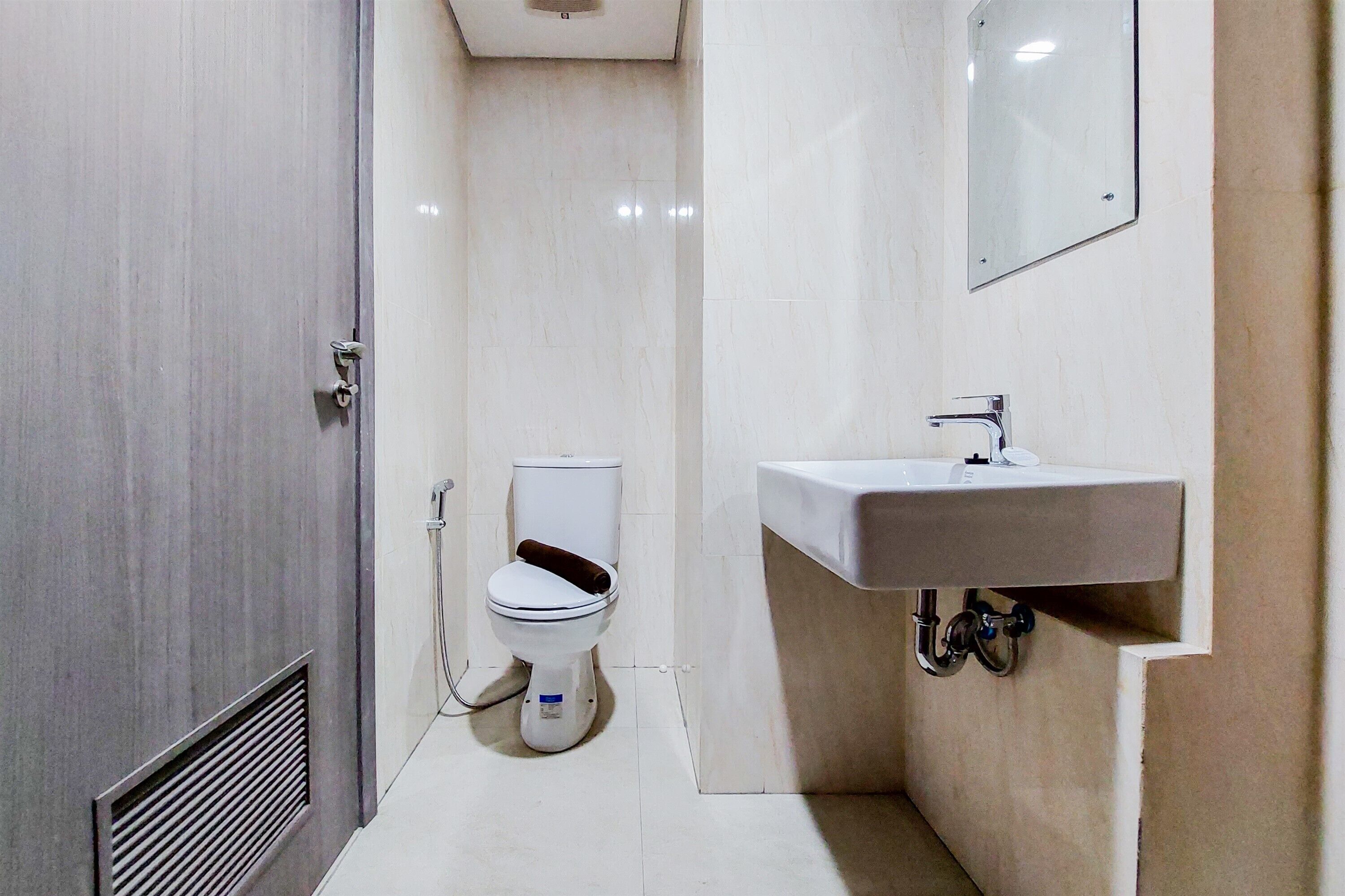 A small, modern bathroom with a toilet, sink, and mirror.