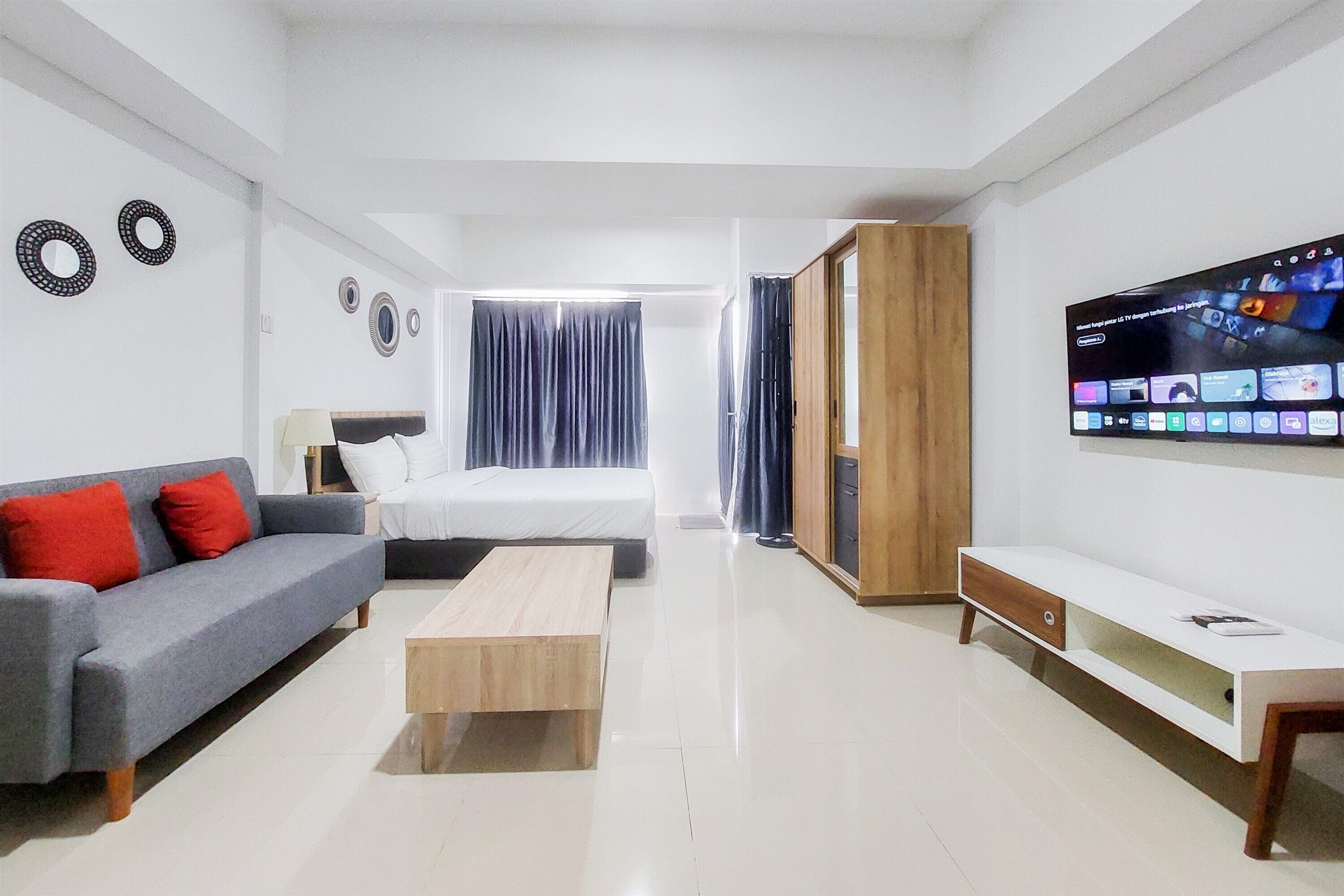Una habitación de hotel moderna con sofá, cama, televisor y un mueble de madera.