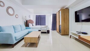 A modern living room with a sofa, a bed, a TV, and a wooden coffee table. - Comfortable And Tidy Studio Tamansari Bintaro Mansion Apartment (South Tangerang)