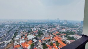 A cityscape with a mix of residential and commercial buildings, including a prominent high-rise in the distance. - Comfortable And Tidy Studio Tamansari Bintaro Mansion Apartment (South Tangerang)