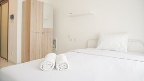 Een hotelkamer met een bed, een houten garderobe en een spiegel.