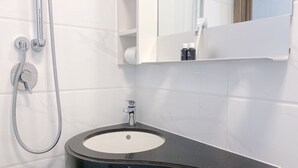 Een badkamer met een wastafel, een spiegel en een douche.
