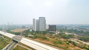 Un edifici alt amb múltiples pisos, envoltat de vegetació i una autopista.
