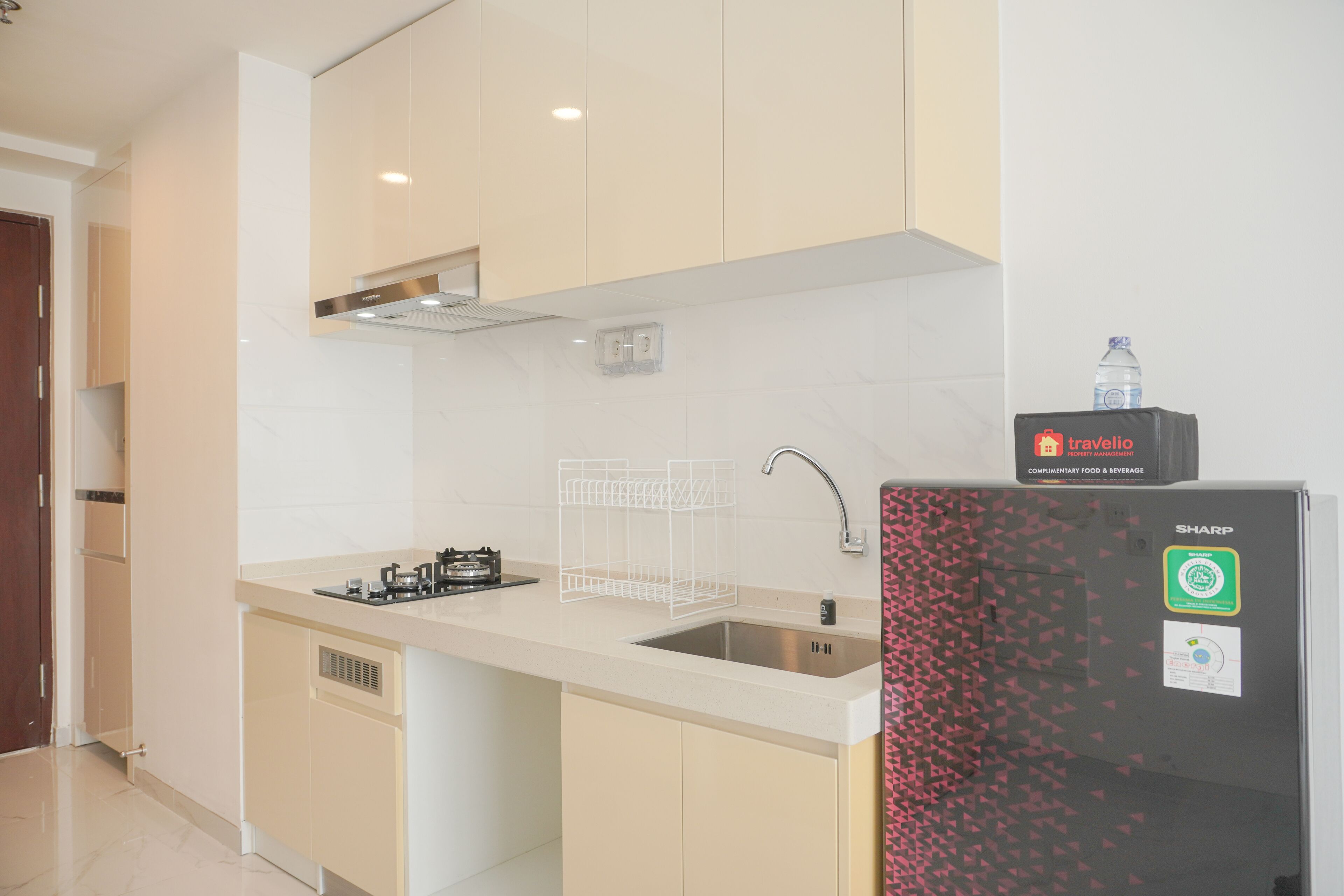 A modern kitchen with a stainless steel sink, a built-in range hood, and a refrigerator with a water dispenser.