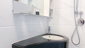 Un bany amb un lavabo negre, un mirall i una dutxa.