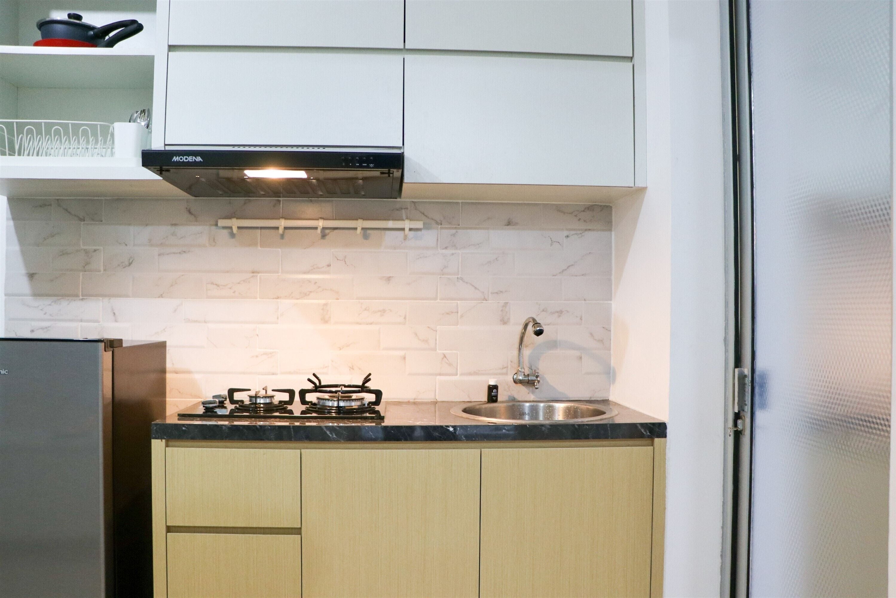 A compact kitchen with a gas stove, a stainless steel sink, and white cabinets.