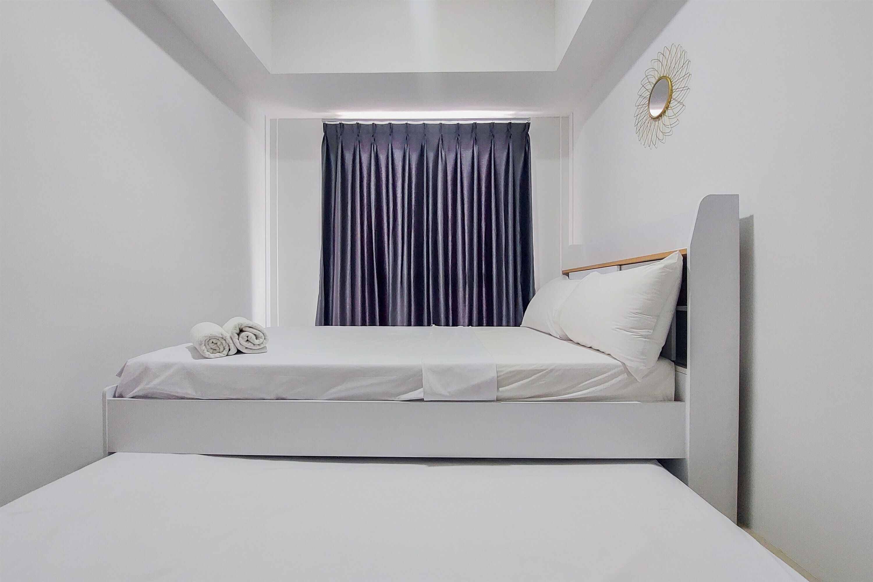 Ein modernes Schlafzimmer mit einem Einzelbett, einem Fenster mit dunklen Vorhängen und einem kleinen Nachttisch.