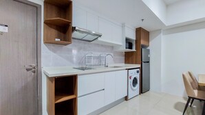 A modern kitchen with white cabinets, a built-in washing machine, and a dining area with a wooden table and chairs.
