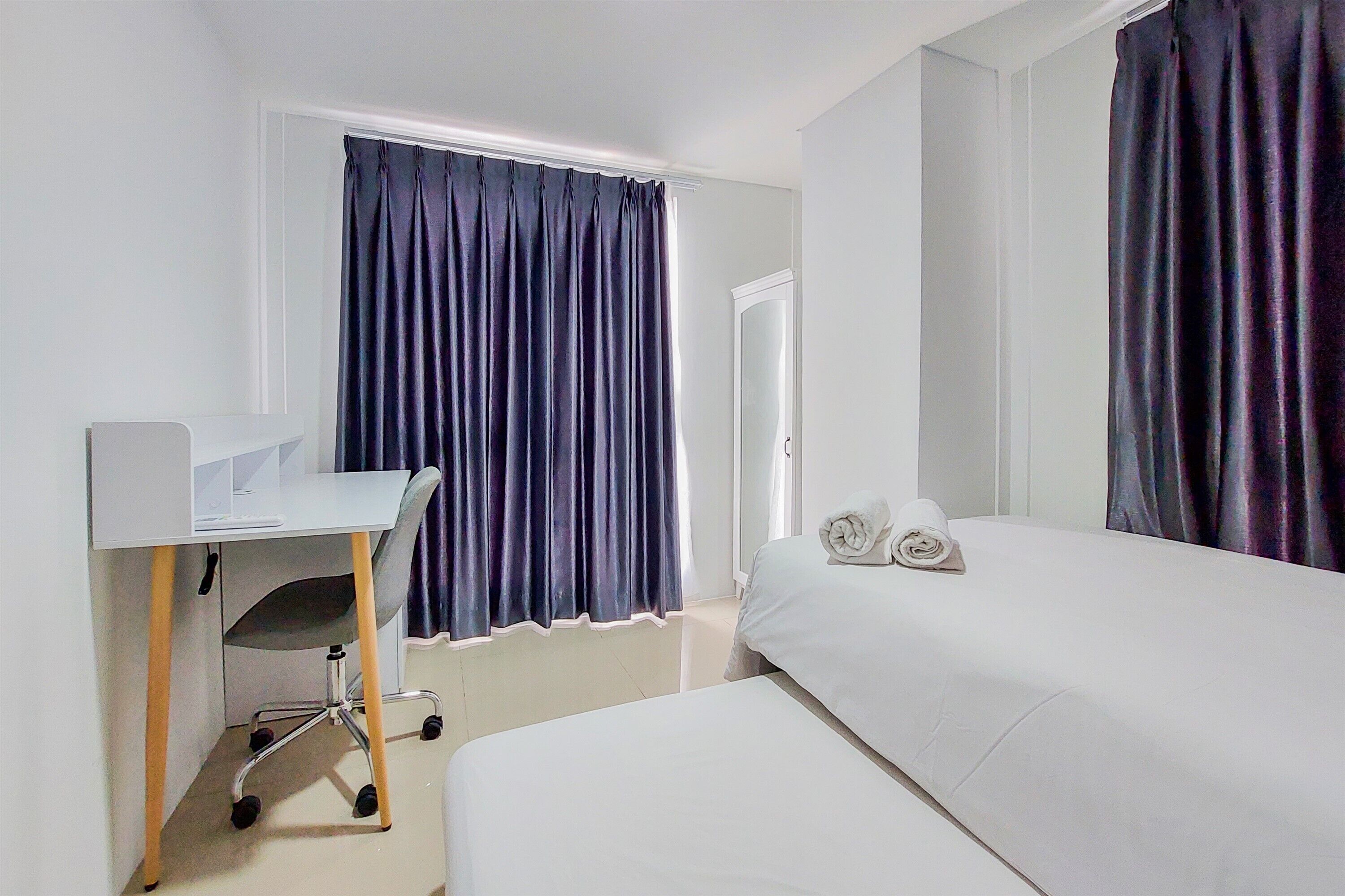 A hotel room with a bed, a desk, and a chair.