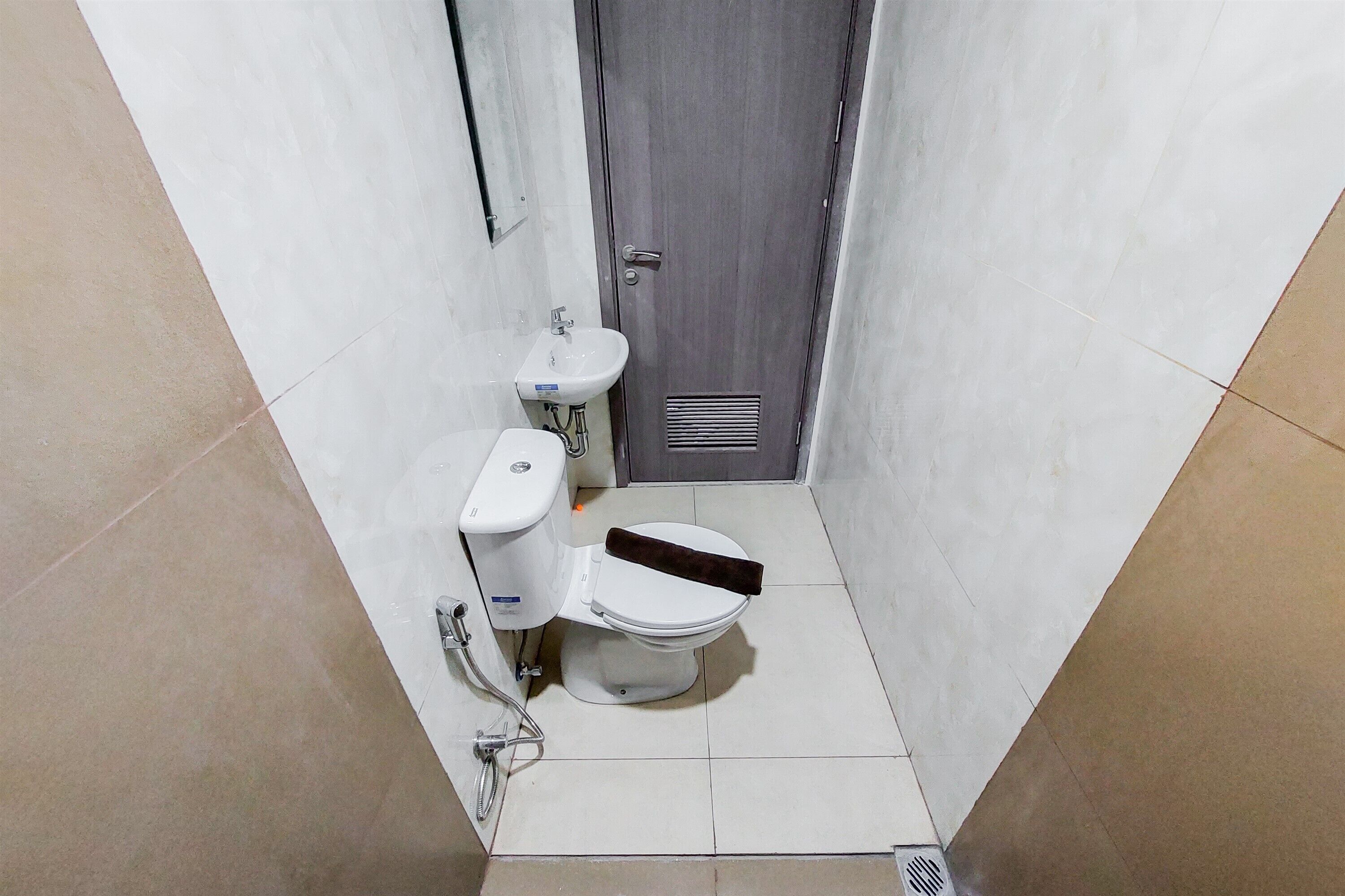 Une petite salle de bain étroite, comprenant des toilettes, un lavabo et un espace douche.