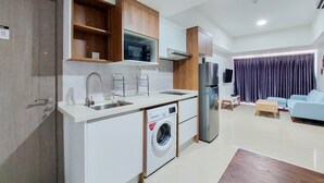A compact kitchen with a washing machine, a microwave, and a refrigerator. - Nice And Homey 3Br Tamansari Bintaro Masion Apartment (South Tangerang)
