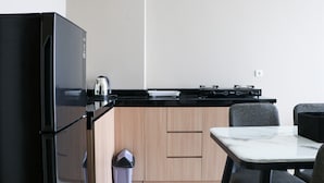 A compact kitchen with a black refrigerator, a stove, and a marble countertop. - Modern And Compact Designed 1Br At Ciputra International Apartment (Jakarta)