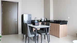 A compact kitchen with a dining area, including a refrigerator, stove, and chairs. - Modern And Compact Designed 1Br At Ciputra International Apartment (Jakarta)