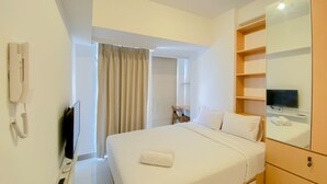 Une chambre d’hôtel équipée d’un lit, d’une télévision, d’un téléphone et d’un miroir.