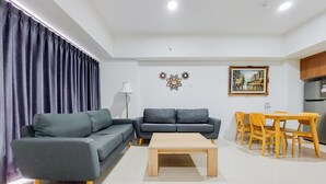 A modern living room with a sectional sofa, a coffee table, and a dining area with chairs and a table.
