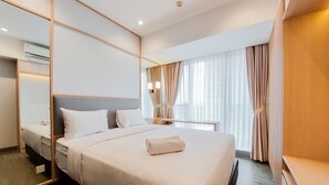 Habitación de hotel con una cama grande, una mesita de noche, un espejo y una ventana con cortinas.