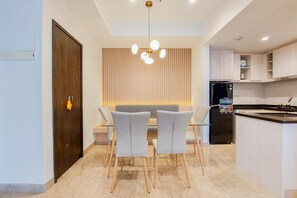 A modern kitchen with a dining area, featuring a built-in oven, a refrigerator, and a seating arrangement with chairs and a table.