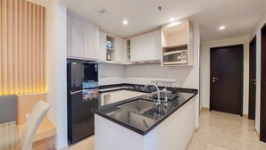 Una cocina moderna con una isla central, electrodomésticos integrados y un rincón comedor con una silla.