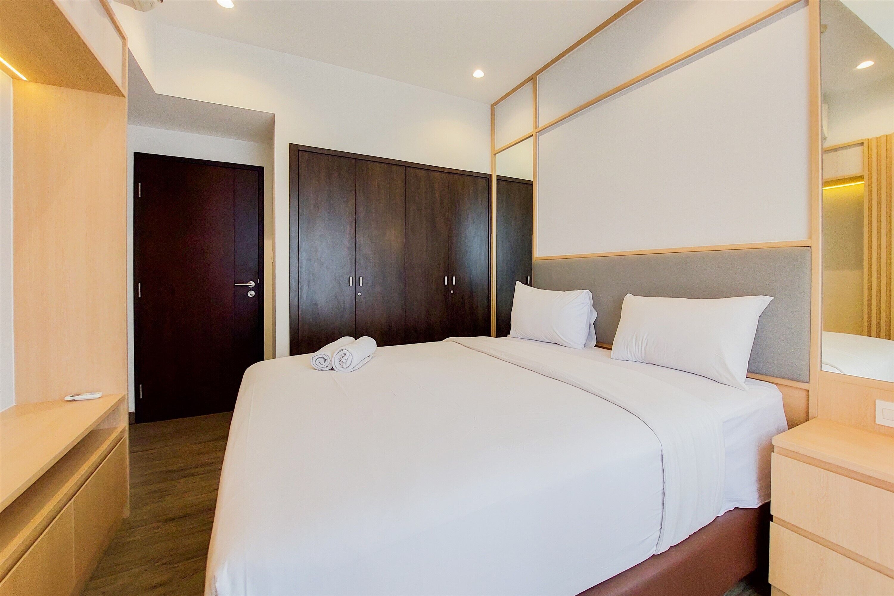 Een moderne hotelkamer met een groot bed, een houten garderobe, een nachtkastje en een spiegel.