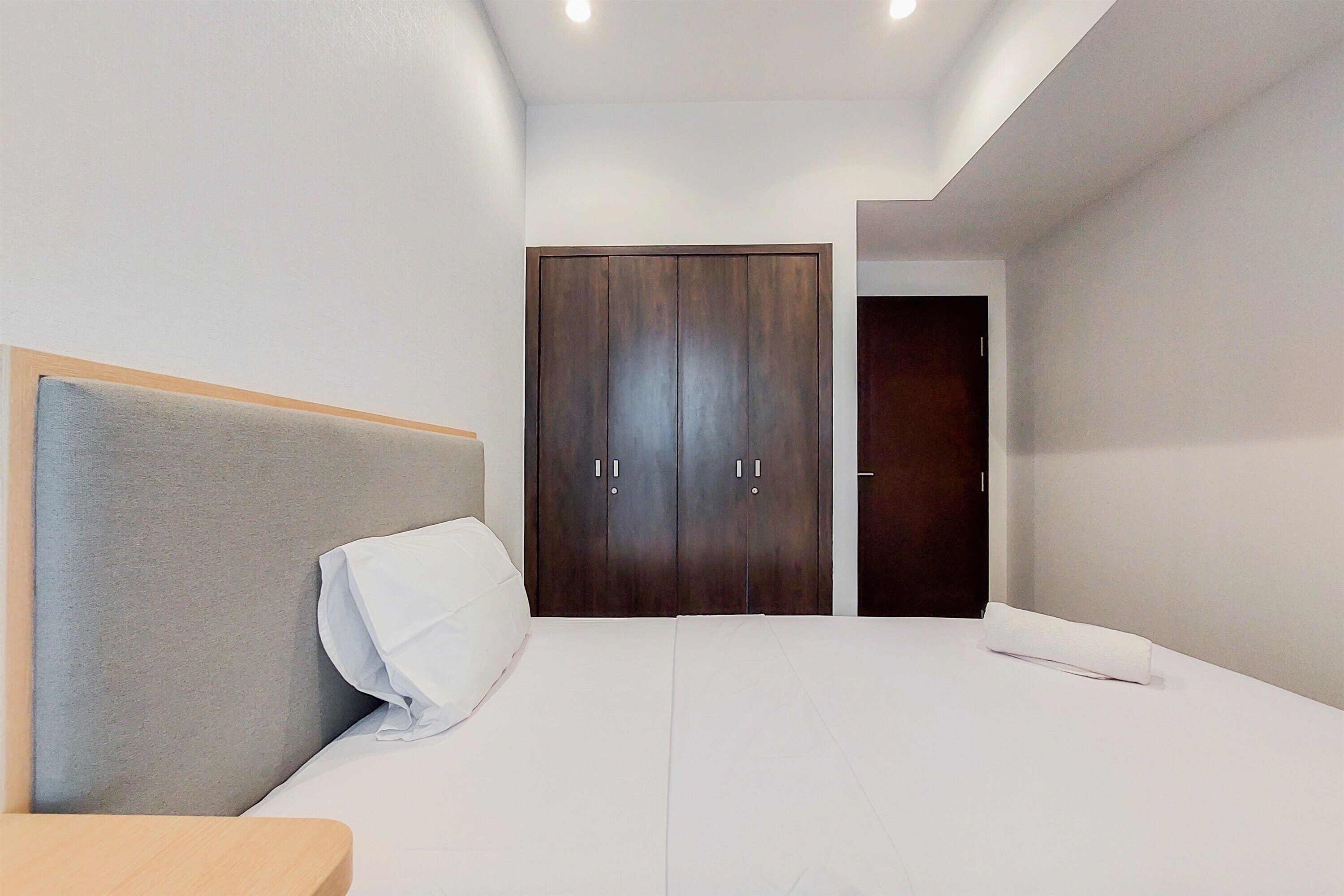 Un dormitorio moderno con una cama grande, un armario de madera y una mesita de noche pequeña.