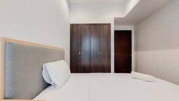 Un dormitorio moderno con una cama grande, un armario de madera y una mesita de noche pequeña.