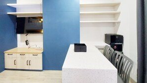 A modern room with a white desk, a blue accent wall, a flat-screen TV, and a black speaker. - Cozy Stay Studio At Mataram City Apartment (Ngaglik)