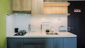 A modern kitchen with a gas stove, sink, and wooden cabinets. - Well Furnished And Cozy Studio Baileys Apartment (South Tangerang)