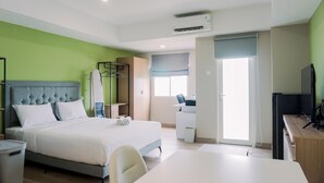 A hotel room with a bed, a desk, a chair, a TV, and a wardrobe. - Well Furnished And Cozy Studio Baileys Apartment (South Tangerang)