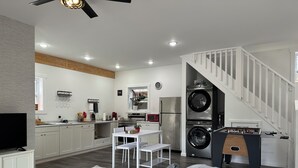 A modern apartment with a kitchen, dining area, and living room. It features a white staircase, a flat-screen TV, and a sofa. - Between Crystal Mountain & TC - Barn - Guest house on 10acres. Pet-friendly! (Interlochen)