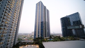 A high-rise building with a modern glass facade, surrounded by other tall buildings. - Warm Designed Studio At Orchard Supermall Mansion Apartment (Surabaya)