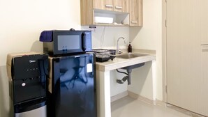 A compact kitchen with a refrigerator, microwave, and sink. - Best Choice And Tidy Studio Meikarta Apartment (Cikarang)
