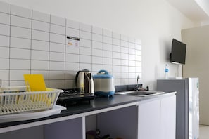 A modern kitchen with white cabinets, a black countertop, a kettle, a toaster, and a sink. - Cozy And Comfort Stay Studio Sayana Bekasi Apartment (Tarumajaya)