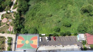 An aerial view of a basketball court with a parking lot and surrounding greenery. - Cozy And Comfort Stay Studio Sayana Bekasi Apartment (Tarumajaya)