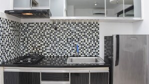 Une cuisine avec un crédence à carreaux noirs et blancs, un évier en acier inoxydable, une cuisinière à gaz et un four encastré.