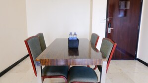 Un salón de conferencias con una mesa de madera, cuatro sillas y dos botellas de agua sobre la mesa.