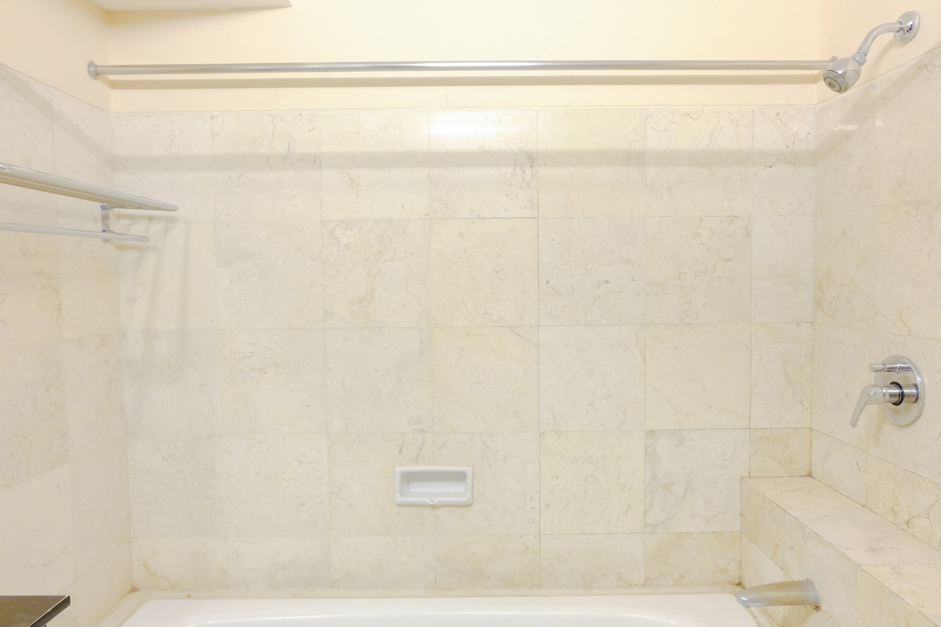 A bathroom with a bathtub, a shower area, and a handrail.