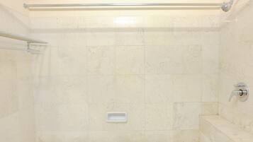 A bathroom with a bathtub, a shower area, and a handrail.