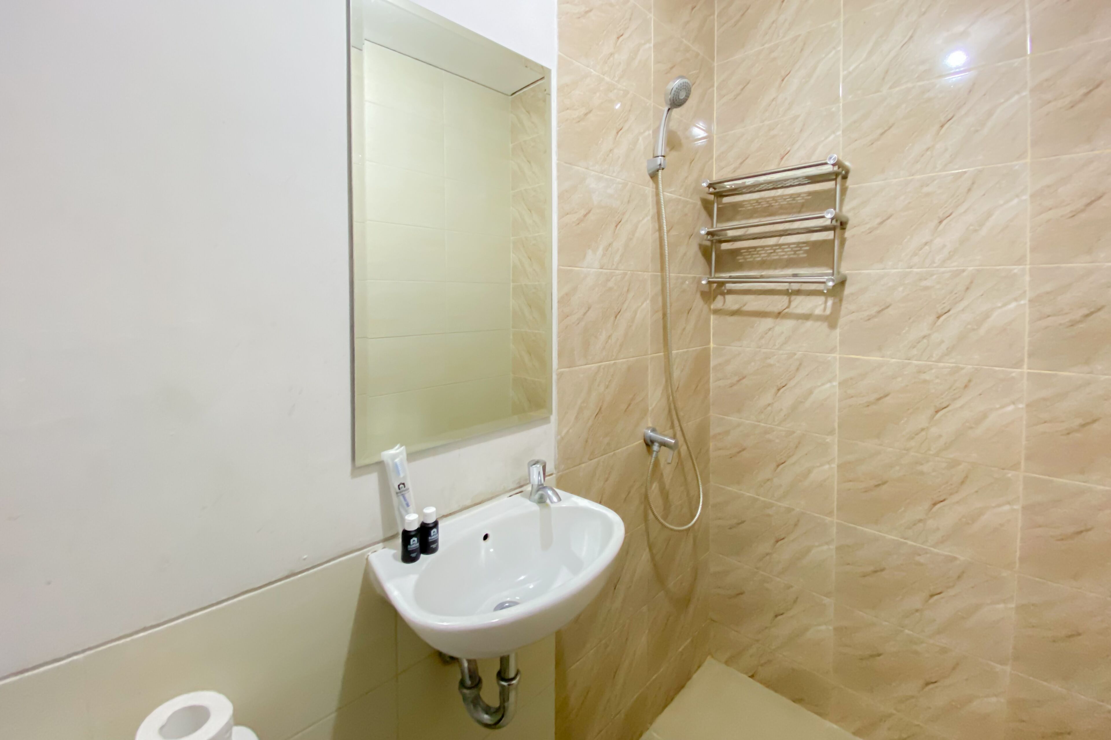 A bathroom with a white sink, a mirror, a shower, and a towel rack.