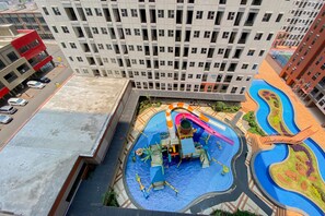 A residential building with a rooftop swimming pool featuring a slide and a water play area. - Minimalist And Cozy Studio Transpark Juanda Bekasi Timur Apartment (Bekasi)