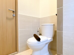 Een wit toilet met een handdoek erop, een houten deur en beige betegelde muren.