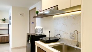 A modern kitchen with a stainless steel sink, a built-in oven, and a microwave. - Spacious And Homey 2Br At Meikarta Apartment (Cikarang)