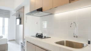 Eine moderne Küche mit Spüle aus Edelstahl, einem Gasherd und Holzschränken.